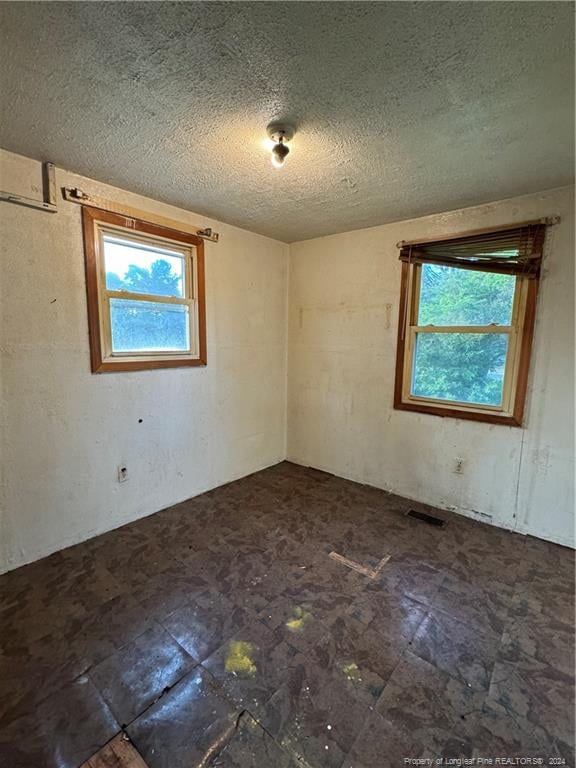 tiled spare room with a textured ceiling and plenty of natural light