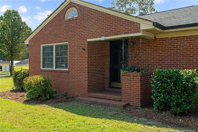 view of exterior entry featuring a lawn