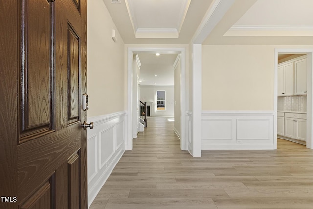 hallway featuring ornamental molding and light hardwood / wood-style floors