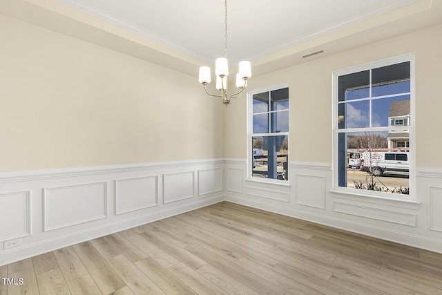 unfurnished room featuring ornamental molding, a notable chandelier, and light hardwood / wood-style floors