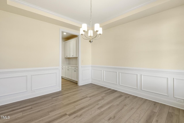 empty room featuring a chandelier, crown molding, and light hardwood / wood-style flooring