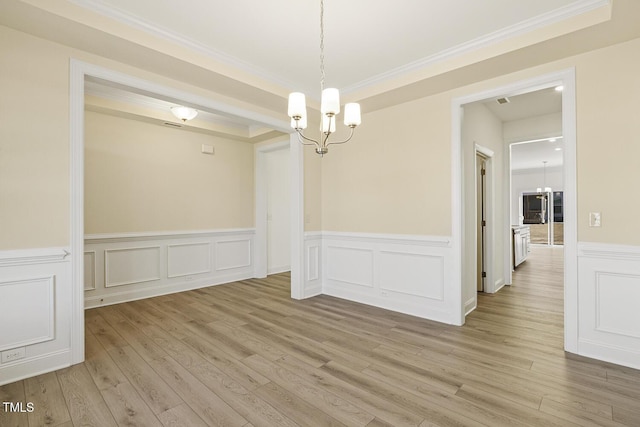 unfurnished dining area featuring a chandelier, crown molding, and light hardwood / wood-style flooring