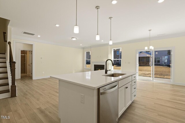 kitchen featuring stainless steel dishwasher, pendant lighting, a kitchen island with sink, white cabinets, and sink