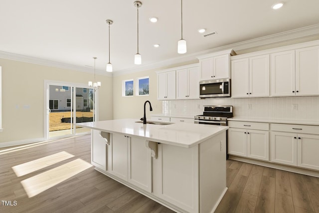 kitchen with pendant lighting, a center island with sink, white cabinetry, appliances with stainless steel finishes, and sink