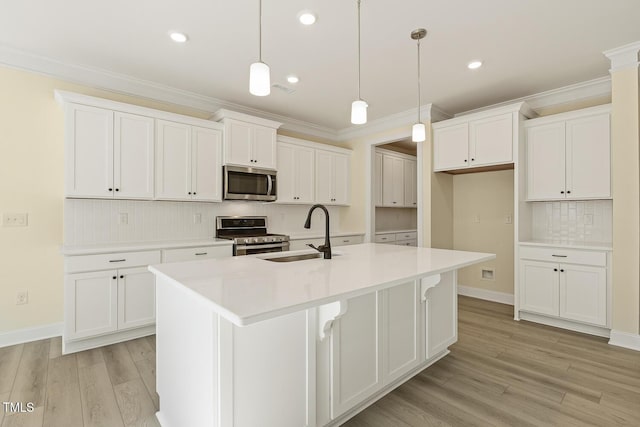 kitchen with a center island with sink, appliances with stainless steel finishes, white cabinetry, decorative light fixtures, and tasteful backsplash