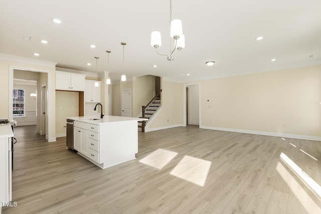 kitchen with white cabinets, light wood-type flooring, pendant lighting, a kitchen island with sink, and a notable chandelier