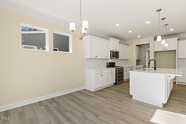 kitchen with sink, pendant lighting, an island with sink, and appliances with stainless steel finishes