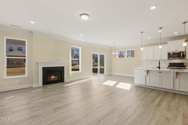 unfurnished living room with ornamental molding, a notable chandelier, and light hardwood / wood-style flooring