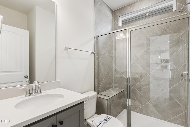 bathroom with toilet, a shower with shower door, and vanity