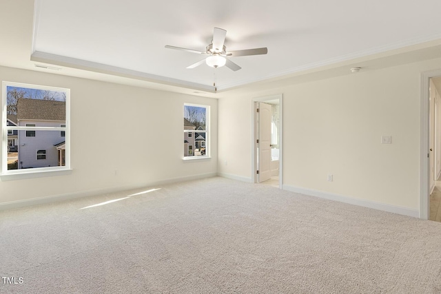 unfurnished room with ceiling fan, light colored carpet, a raised ceiling, and crown molding