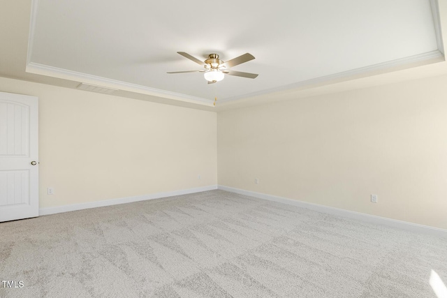 spare room with a raised ceiling, ceiling fan, carpet, and ornamental molding