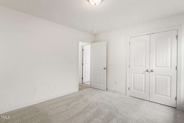 unfurnished bedroom with light colored carpet and a closet