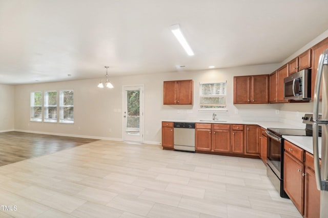 kitchen with appliances with stainless steel finishes, plenty of natural light, an inviting chandelier, and sink