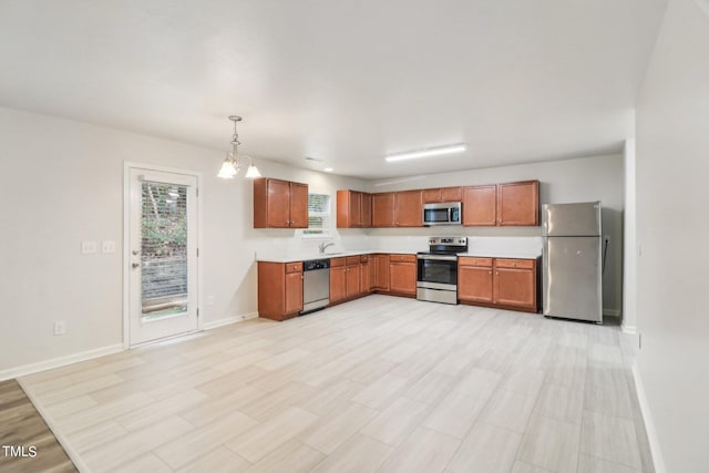 kitchen featuring an inviting chandelier, decorative light fixtures, light wood-type flooring, stainless steel appliances, and sink