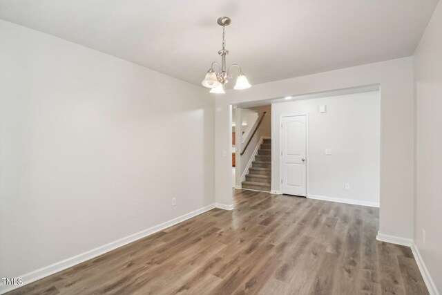 unfurnished room featuring hardwood / wood-style floors and a notable chandelier