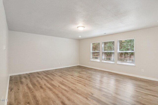 empty room featuring a textured ceiling and light hardwood / wood-style flooring