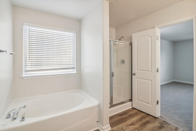 bathroom with a wealth of natural light, hardwood / wood-style flooring, and plus walk in shower