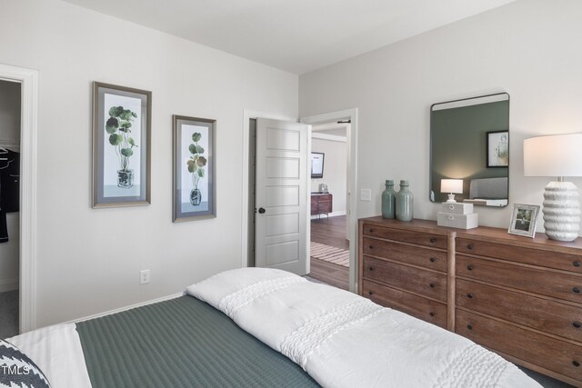 bedroom featuring a spacious closet and wood finished floors