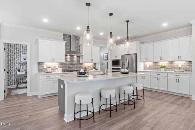 kitchen with crown molding, stainless steel appliances, light countertops, a sink, and wall chimney exhaust hood