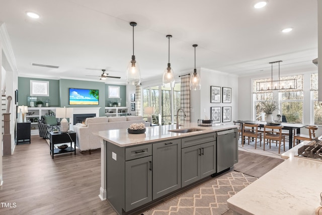 kitchen with crown molding, gray cabinetry, a sink, dishwasher, and a lit fireplace