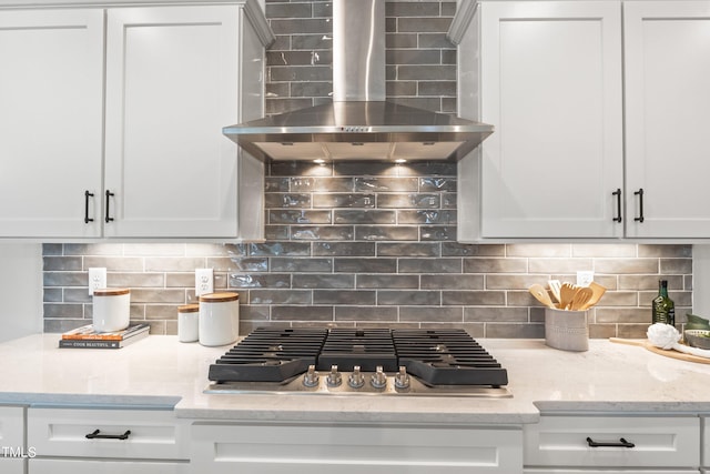 kitchen with stainless steel gas cooktop, backsplash, and wall chimney exhaust hood