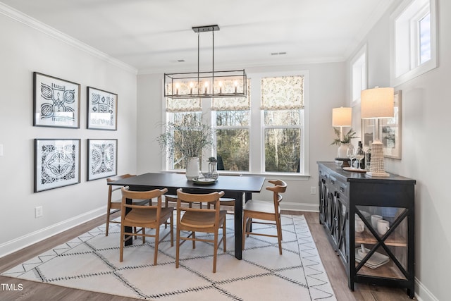 dining area featuring a notable chandelier, wood finished floors, visible vents, baseboards, and crown molding