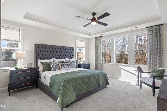 bedroom with ornamental molding, a raised ceiling, visible vents, and light colored carpet