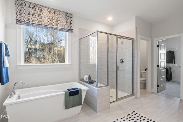 bathroom featuring a tub to relax in, a stall shower, and toilet