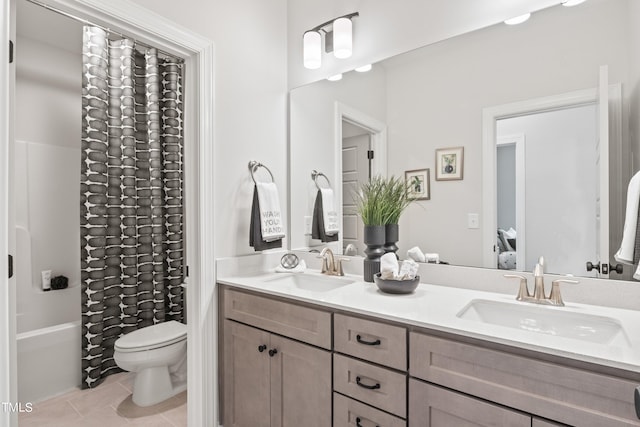 full bathroom featuring toilet, double vanity, a sink, and tile patterned floors