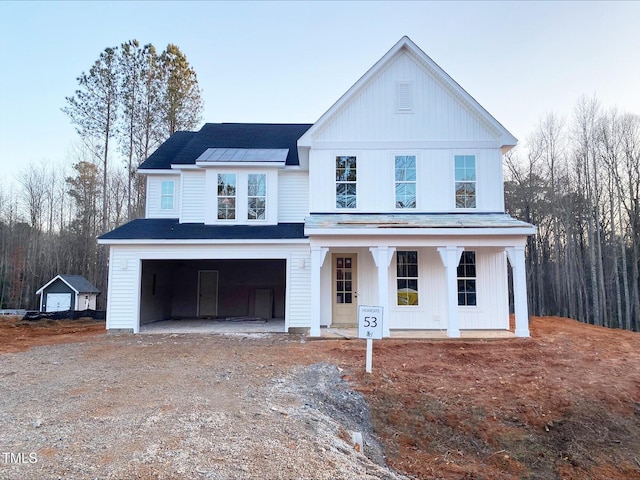 view of front of property featuring covered porch, dirt driveway, board and batten siding, and an attached garage