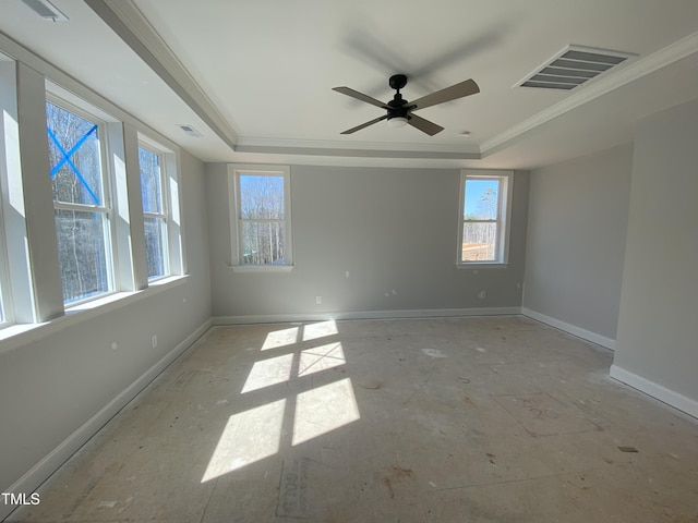 spare room with a tray ceiling, visible vents, and baseboards