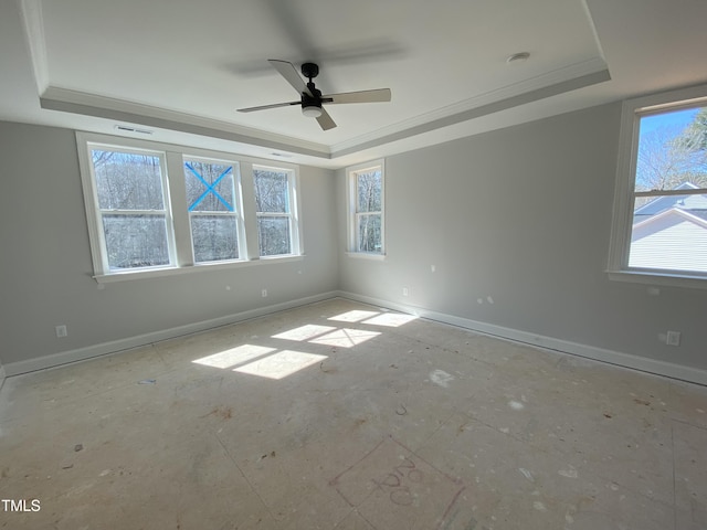 unfurnished room with ornamental molding, a tray ceiling, and baseboards