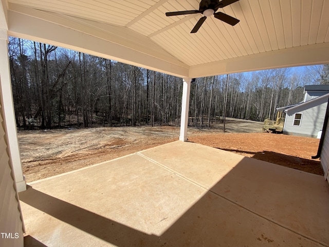 view of patio featuring a view of trees and a ceiling fan