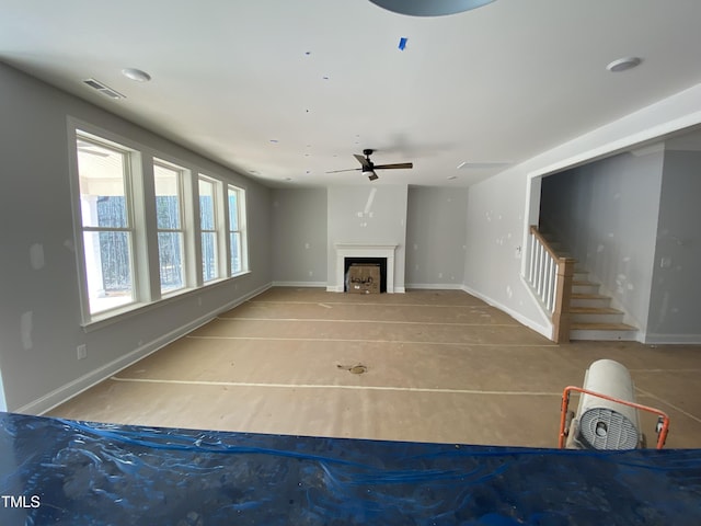 unfurnished living room with stairs, a fireplace, visible vents, and baseboards