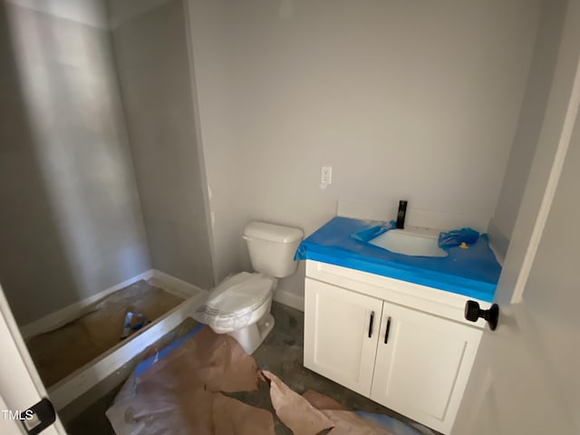 bathroom with baseboards, vanity, and toilet