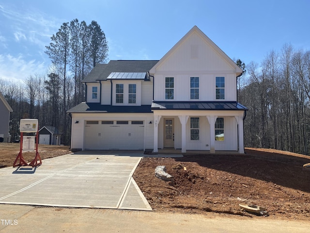 modern farmhouse featuring an attached garage, a standing seam roof, driveway, and a porch