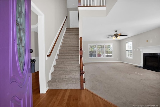 foyer entrance featuring stairs, carpet, a fireplace with flush hearth, and baseboards