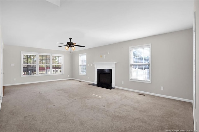 unfurnished living room with light carpet, a fireplace with flush hearth, and a wealth of natural light