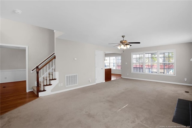 unfurnished living room with baseboards, visible vents, a ceiling fan, stairs, and carpet floors