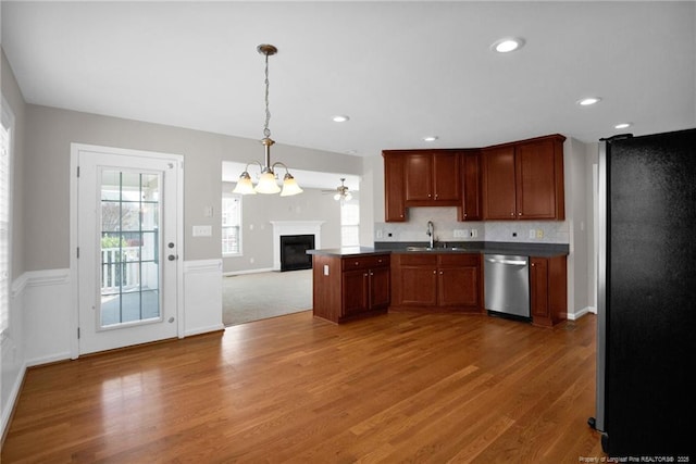 kitchen with dark countertops, appliances with stainless steel finishes, open floor plan, pendant lighting, and a sink