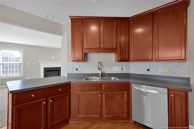 kitchen featuring a peninsula, a sink, backsplash, dishwasher, and dark countertops