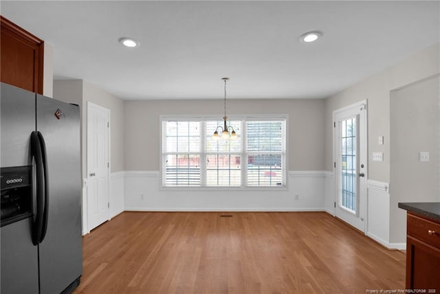 kitchen with dark countertops, light wood-style floors, stainless steel refrigerator with ice dispenser, and pendant lighting