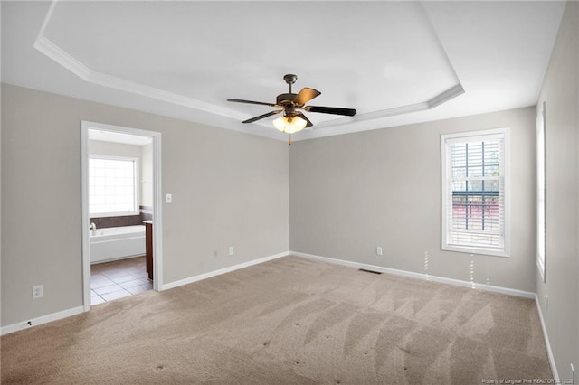 spare room with light carpet, baseboards, visible vents, a ceiling fan, and a tray ceiling