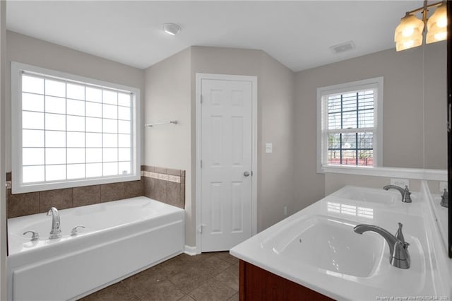 bathroom with double vanity, a garden tub, tile patterned flooring, and a sink