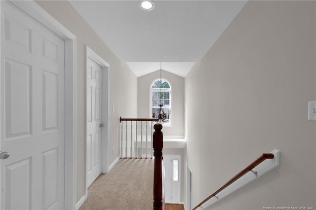 hallway with carpet floors, lofted ceiling, baseboards, and an upstairs landing