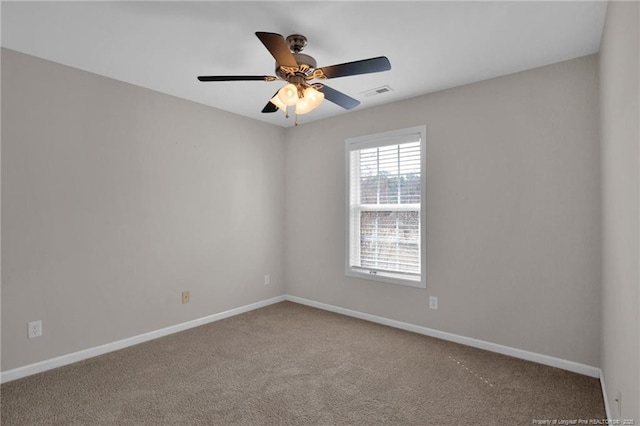 carpeted spare room with baseboards, visible vents, and ceiling fan