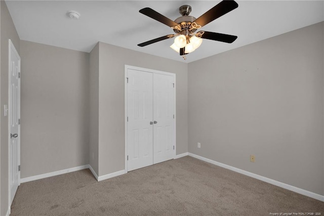 unfurnished bedroom featuring a ceiling fan, baseboards, a closet, and light colored carpet