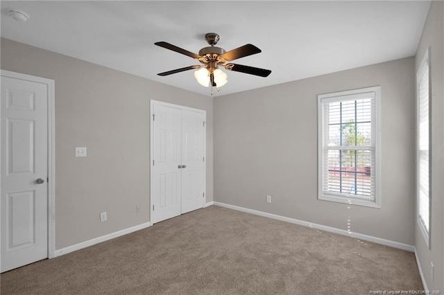 unfurnished bedroom featuring light carpet, a closet, a ceiling fan, and baseboards