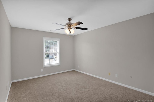 carpeted spare room with ceiling fan and baseboards