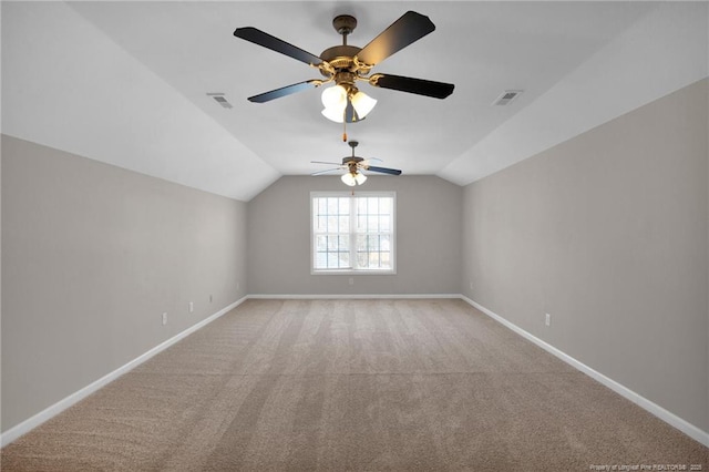 empty room with vaulted ceiling, light carpet, visible vents, and baseboards